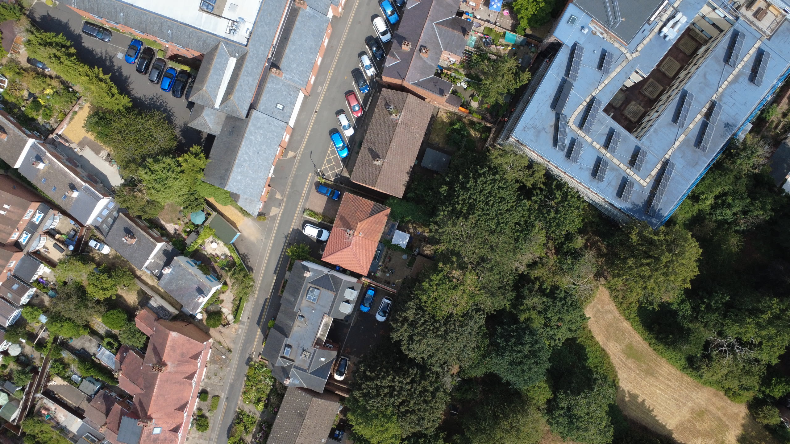 Nadir view straight down over a street of terraced houses, gardens and parked cars